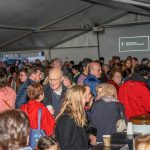 Zahlreiche Menschen haben sich zu einem gemütlichen Beisammensein im Zelt vor der Markuskirche versammelt. Es gibt Leberkässemmel, Reindling sowie Kaffee und verschiedene Getränke (© Herr Gerhard Pulsinger).